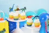 dinosaur cupcake toppers, dinosaur cupcake wrappers on cupcakes on white cake stands. Blue and teal balloons in the background