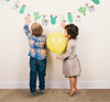 2 kids reaching for llama and cactus party garland