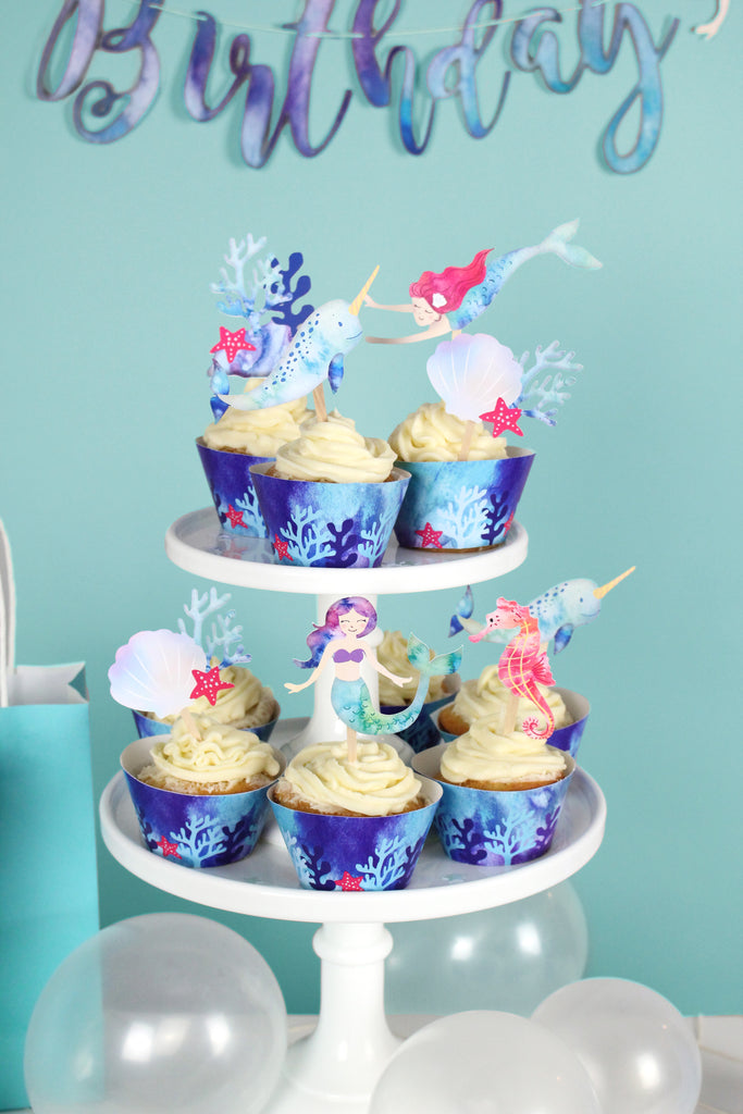 mermaid cupcake toppers on cupcakes wrapped with blue ocean print cupcake wrappers 