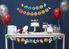 trip to the moon outer space party scene with a birthday banner, a garland, cupcake toppers, balloons and party hats